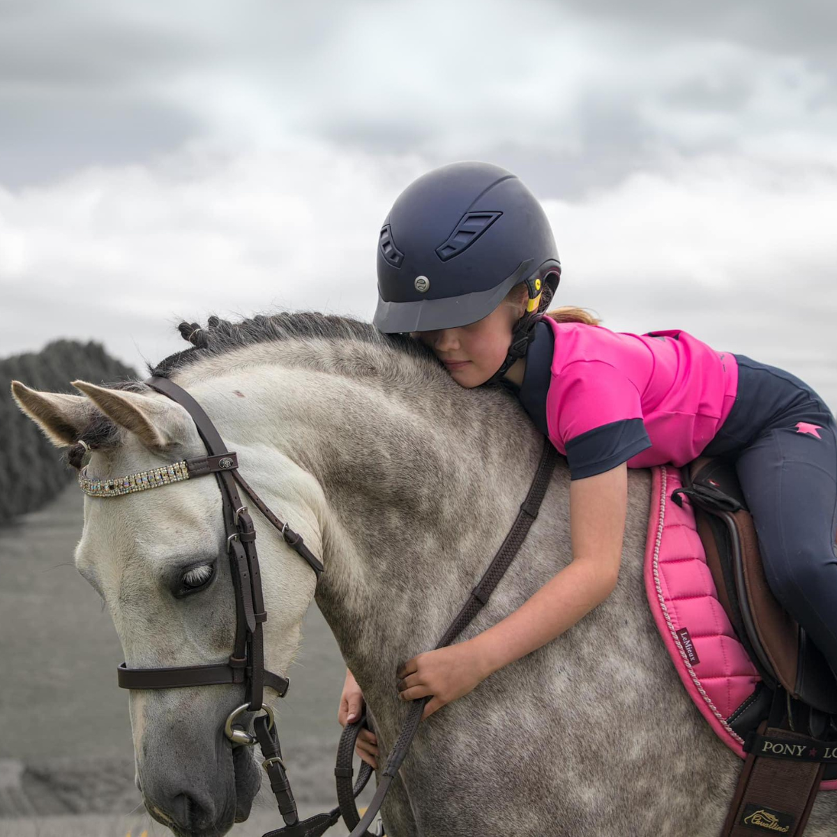 Rider in pink vest and helmet wearing matching polo with breeches for kids
