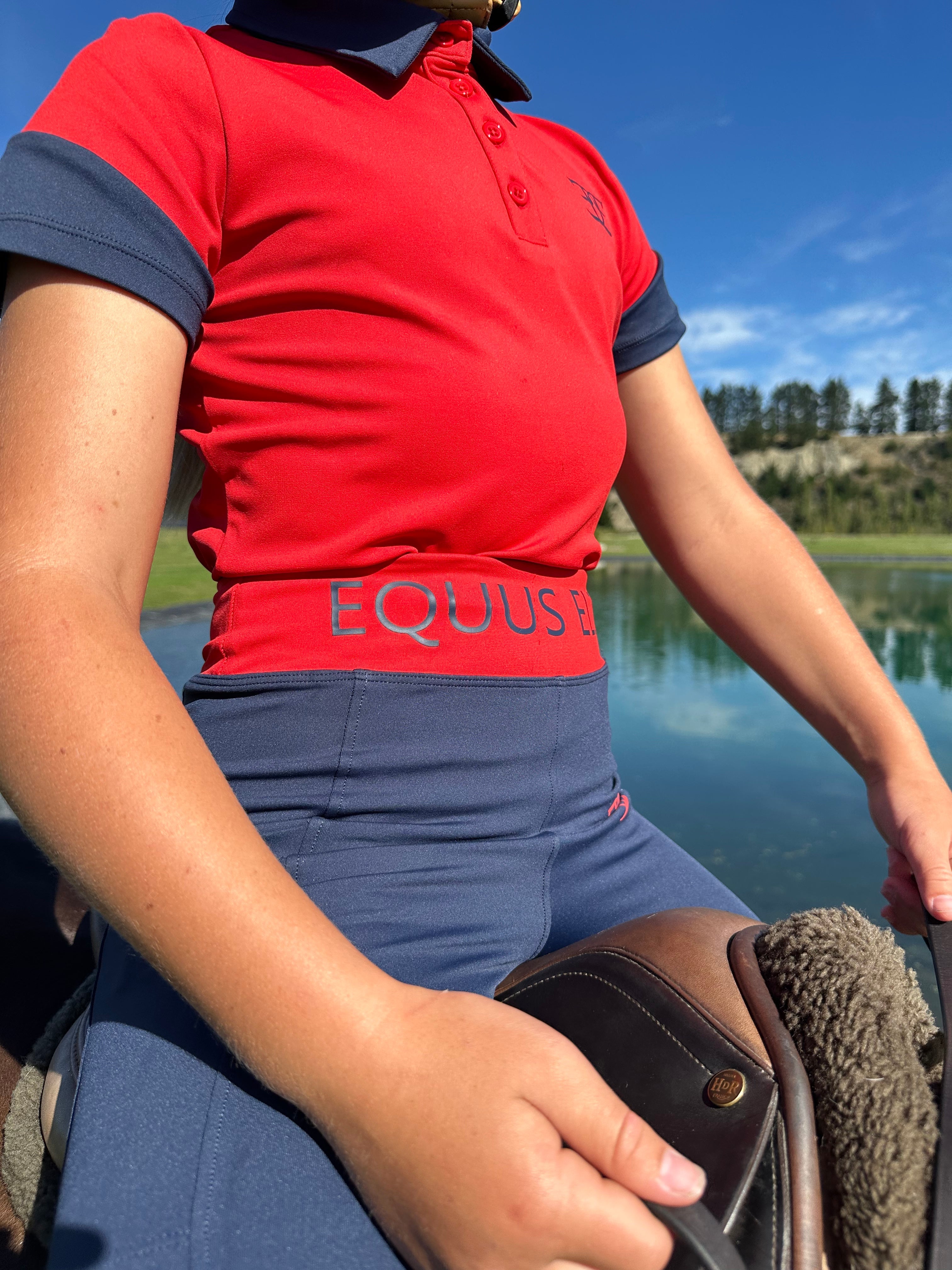 Child in a red polo shirt and blue shorts, wearing Kids X Training Tights on horseback