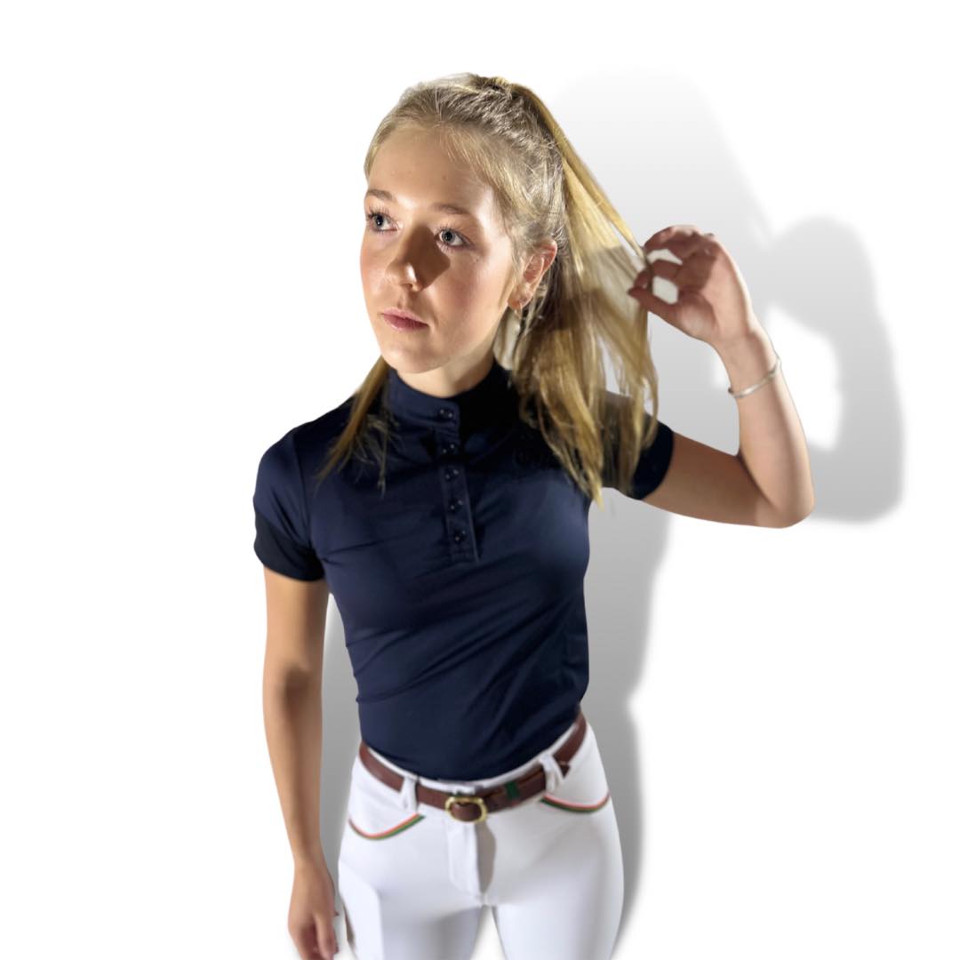 Young blonde woman in navy blue polo shirt and white pants, featuring Performance Show shirt