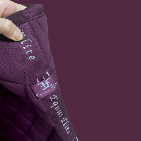 Purple quilted fabric of Equus Elite Saddle Pad featuring embroidered text, perfect for breeches